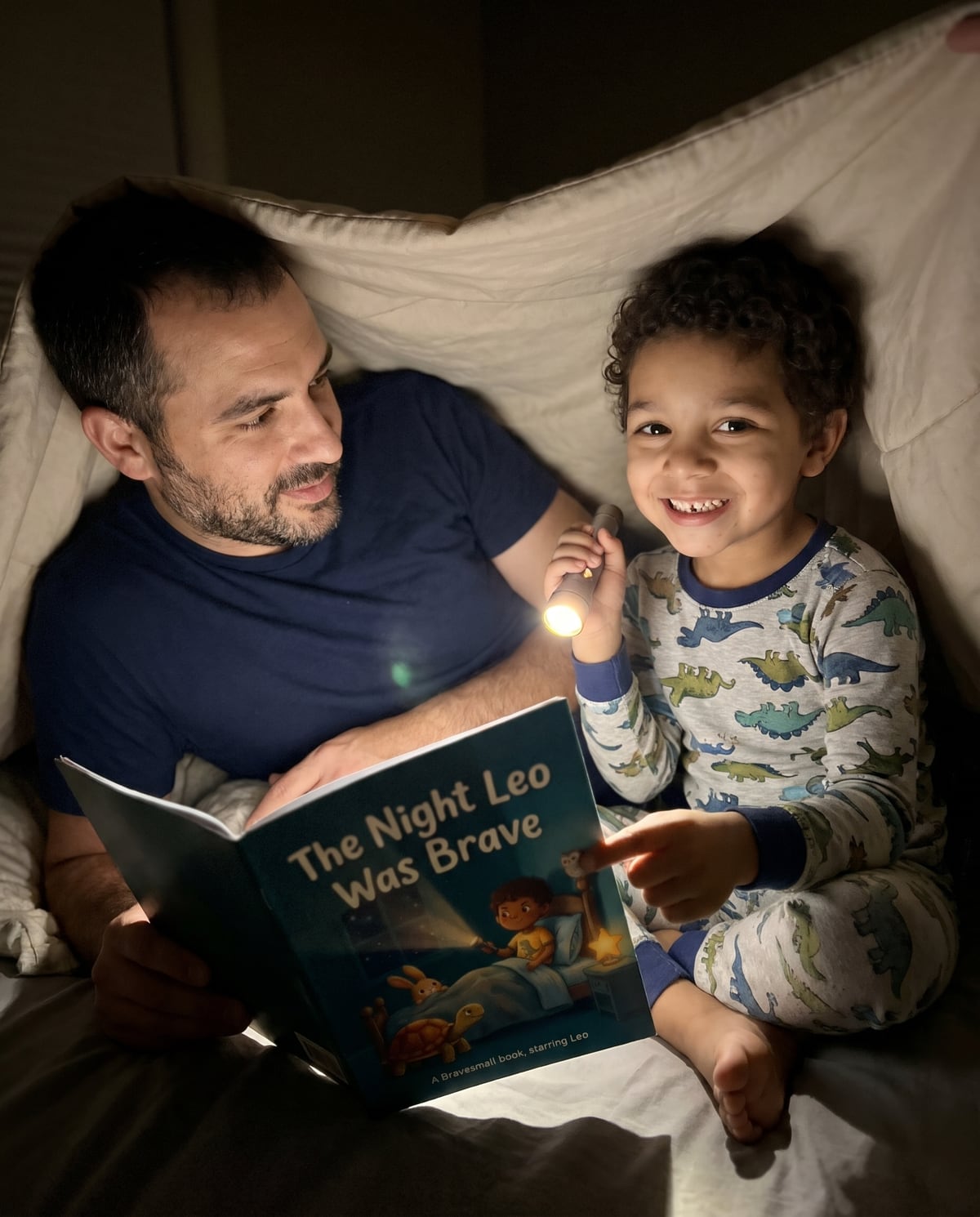 A father and son in a blanket fort reading The Night Leo Was Brave